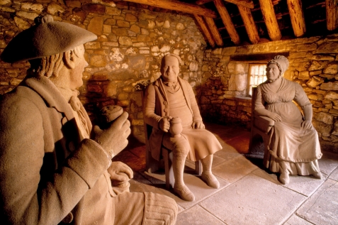 Life-sized stone figures of Souter Johnnie, Tam the innkeeper and his wife in the restored alehouse at Souter Johnnie's cottage, Ayrshire.